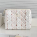 Détail d'une trousse de maquillage matelassée aux motifs floraux et fermeture éclair - Pochette de taille moyenne / Fleur rouge à rayures verticales