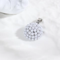 Vue macro d'un pendentif perle blanche sphérique avec fermoir métallique sur fond blanc - Sphère Argentée