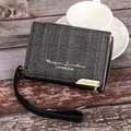 Close-up of herringbone texture on dark grey wallet with wrist strap on wooden surface - Black