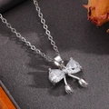 Close-up of silver bow pendant necklace with heart-shaped crystals on dark background - Silver Two Diamond Bowknot Necklace