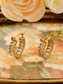 Détail de boucles d'oreilles dorées en C avec zircons sur une assiette fleurie rétro - ZHE2399 - Strass Blanc / Or 18K