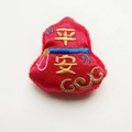 Close-up of red Chinese New Year Pingan charm with gold embroidery, 4.8cm height - Safety and Peace