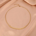 Collar minimalista de hojas doradas sobre un elegante fondo de satén de seda champán - Dorado