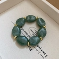 Detail view of irregular oval green marble acrylic beads and golden metal spacer beads - Green