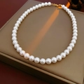 Dettaglio ravvicinato di perle bianche lucide su una collana con chiusura dorata - Stile di Specifica 10mm (HN7011)