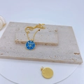 Macro detail of gold-plated copper pendant featuring blue enamel evil eye and star designs - Blue Round Evil Eye