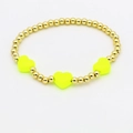 Primo piano del bracciale con perle dorate e tre cuori in smalto giallo fluo vivace - Giallo