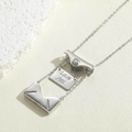 Makroaufnahme der silbernen Umschlag-Medaillon-Kette mit Love You Gravur im Inneren - Weißgold Zirkonia Stil
