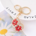 Detailed view of heart-shaped rhinestone keychain with red flower accents on a plate - White Rhinestone Red Flower Heart