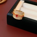 Macro shot of luxury gold ring with emerald-cut red stone and paved zircon details - Gold-Red Zirconia