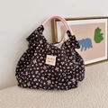 Dettaglio del tessuto a bolle floreali e dell'etichetta del logo sulla borsa nera - Nero con fiori rosa
