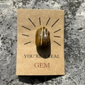 Gros plan d'une pierre œil de tigre sur carte kraft avec texte YOU'RE A REAL GEM - Bracelet en pierre œil de tigre