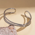 Detail view of multilayer geometric silver bangle set on a decorative rock pedestal - Mirror Multi-layer Style / Silver