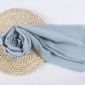 Dusty blue chiffon hijab scarf with pearl texture rolled in a rose shape on woven mat - 93