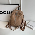 Detailed view of khaki pebbled leather backpack with multiple zippers and woven strap - Khaki