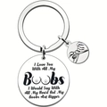 Macro detail of engraved silver stainless steel key ring with humorous round pendants - Boobs Bigger Humorous Message