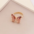 Detailed macro view of an adjustable gold butterfly ring with red gradient crystal wings - Coffee