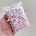 Polished natural pink rose quartz crystal chips in a transparent bag held by hand - Rose Quartz / 5-7mm 100g