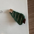 Close-up of a handmade crochet Christmas tree hair clip with a star on open book pages - Christmas Tree - Yellow Star