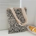 Close-up of a beige knitted tote bag with black pattern and magnetic snap closure - Black Seed