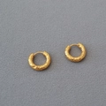 Detail shot of vintage gold hammered texture hoop earrings on a grey fabric background - Gold