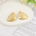 Golden irregular triangle earrings with lava texture on white tiered display stand - Gold EH003 (Wave Triangle)