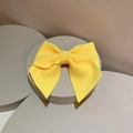Detalle de un lazo amarillo brillante con textura acanalada en soporte gris - Clip para el pelo / Amarillo