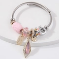 Silver beaded bracelet with pink crystal teardrop and August Harmony charms on white surface - Pink