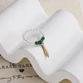 Beaded elastic ring with transparent crystal beads and a golden metal feather charm - Feather Charm