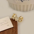 Detalle de anillo dorado con corazones calados y circonitas en soporte de madera - Dorado