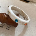 Dettaglio del bracciale in acrilico marmorizzato con gemme colorate e castoni dorati lucidi - Bianco Multicolore