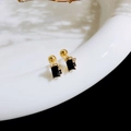 Macro shot of gold stud earrings featuring black stones and delicate bow details - Square Bow / Gold