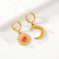Detalle de pendientes asimétricos de sol y luna dorados con piedras color naranja - Dorado