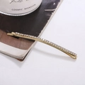 Detail of a minimalist gold hair clip with sparkling rhinestones in an elegant setting - Gold / White Zirconia