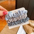 Three leopard print fabric scrunchies in light blue, gray and spotted patterns held by hand - Blue Combo