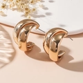 Close-up of golden chunky C-shaped hoop earrings with a high-shine metallic finish - Stud Earrings / Gold