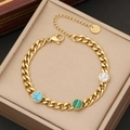Gouden roestvrijstalen kettingarmband met turkoois en malachiet in een sieradendoosje - Stippenstijl