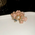 Detailed close-up of a pink enamel flower brooch with gold plating and a center pearl - French Flower Style / Gold Pink
