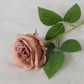 Single velvet artificial rose in dusty pink with realistic green leaves on white fur - Coffee