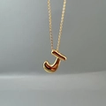 Close-up of a glossy golden letter J pendant on a delicate chain necklace - Letter J Single Pendant