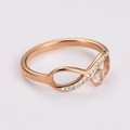 Detail of rose gold infinity ring with white crystals and heart stone on white background - US 6 / Rose Gold