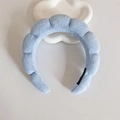 Light blue sponge cloud headband made of soft terry cloth fabric on a display stand - Blue