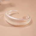 Macro view of iridescent acrylic geometric bangle with vertical ribbed texture detail - Fine Texture
