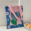 Detail of blue knitted tote bag with pink flower patterns and silver magnetic snap closure - Tulip Blue