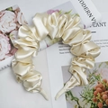 Elegante cerchietto in raso plissettato beige con trama ondulata su una rivista - Champagne
