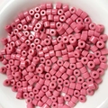 Dettaglio di perline acriliche cilindriche rosa da 6mm in una ciotola bianca liscia - Rosa Rugiada