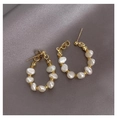 Détail de boucles d'oreilles créoles avec perles baroques naturelles sur tissu gris texturé - Créoles en Perles / Doré