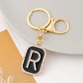 Detail of a gold letter R keychain with black enamel and sparkling rhinestones - Letter R