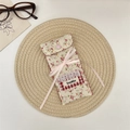 Detailed close-up of floral fabric glasses pouch with pink bow and lace pocket detail - Red