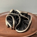 Detail of a large satin scrunchie in black with champagne trim on a dark wood tray - Large / Black